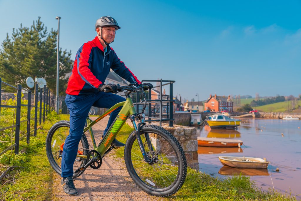 Man riding Ampere electric bike on a Cycle path by the harbor